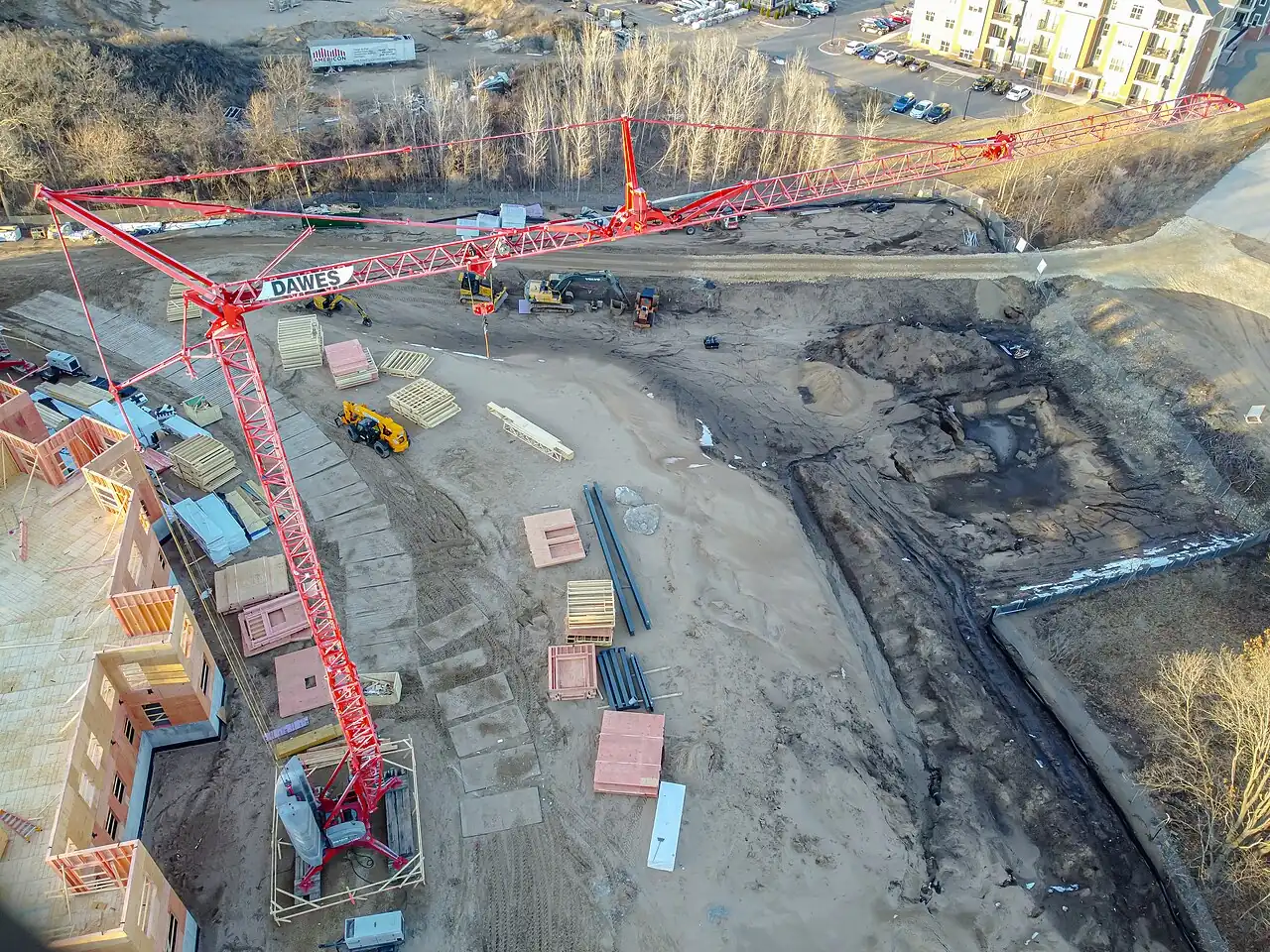 Tower crane over an active construction site with materials staged
